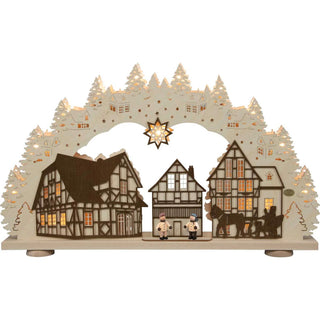LED-Schwibbogen „Kontraste“ aus naturfarbenem und dunkel abgesetztem Holz mit detailreicher 3D-Dorfszene. Fachwerkhäuser, zwei handbemalte Figuren und ein Pferdegespann werden von 15 warmweißen LEDs stimmungsvoll beleuchtet. Der 66 cm breite Schwibbogen erzeugt durch den Hell-Dunkel-Kontrast und die mehrlagige Gestaltung eine besondere Tiefenwirkung.