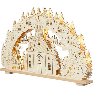 Holzfarbener LED‑Schwibbogen mit der detailreich gestalteten Seiffener Kirche im Zentrum. Umgeben wird die Kirche von hohen, fein ausgesägten Tannenbäumen, kleinen Häusern und winterlichen Szenerien. Links steht eine geschnitzte Figurengruppe mit Bergmann und Engel, rechts ein Schneemann mit weiteren Dekorelementen. Der Schwibbogen ist reich durchbrochen, mit vielen kleinen Stern‑ und Fensterdetails, und besitzt eine geschwungene Bogenform. Gesamtlänge des Bogens: 66 cm. beleuchtet, seitliche Ansicht