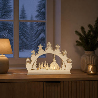 LED-Schwibbogen Mini „Kurrende“ aus naturfarbenem Holz mit traditioneller Weihnachtsszene. Das Motiv zeigt vier Kurrendesänger vor einer Kirche, umgeben von Tannenbäumen und einem dekorativen Bogen mit warmweißer LED-Beleuchtung. Der 24 cm breite Mini-Schwibbogen sorgt für eine stimmungsvolle Weihnachtsatmosphäre und ist ideal für Fensterbank, Regal oder Tisch.
