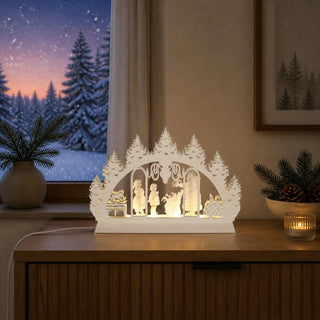 LED-Schwibbogen Mini „Weihnachtsmann“ aus naturfarbenem Holz mit winterlicher 3D-Szene. Das Motiv zeigt den Weihnachtsmann mit Geschenkesack, zwei Kinder, einen Schlitten und einen geschmückten Tannenbaum, umrahmt von stilisierten Tannen. Die integrierte LED-Beleuchtung sorgt für warmes, stimmungsvolles Licht. Der 24 cm breite Mini-Schwibbogen ist eine festliche Weihnachtsdekoration für kleine Fensterbänke, Regale oder Tische.