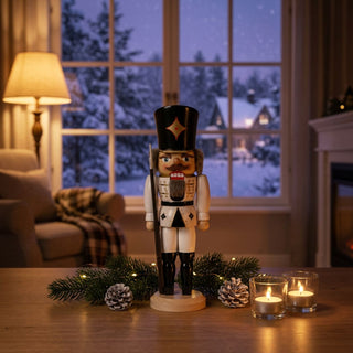 Nussknacker „Soldat“ in weißer Uniform (36 cm) mit Gewehr, auf einem Tisch mit Kerzen und Tannenzweigen vor winterlichem Fenster.