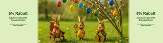 Banner mit Osterdekoration: Drei dekorative Hasenfiguren aus Holz sitzen auf einer Wiese unter einem Zweig mit bunten Ostereiern. Links und rechts steht der Text „5% Rabatt auf unsere gesamte Osterkollektion – der Rabatt wird im Warenkorb direkt abgezogen!“.