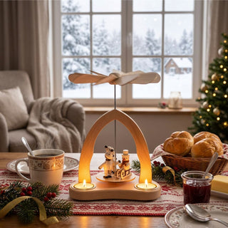Weihnachtspyramide „Winterkinder“ aus naturbelassenem Holz (20 cm) für 3 Teelichte, mit drehendem Flügelrad und winterlicher Figurenszene, dekoriert auf einem festlich gedeckten Tisch vor verschneiter Fensterkulisse.
