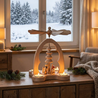 Weihnachtspyramide „Winterkinder“ aus naturbelassenem Holz (21 cm) für vier Teelichter mit Flügelrad. Geschwungene Bogenform mit Szene aus Winterkind-Figur und Schneemann neben Tannenbaum. Auf einer Kommode vor verschneitem Fenster, stimmungsvoll beleuchtet und mit Tannenzweigen dekoriert.