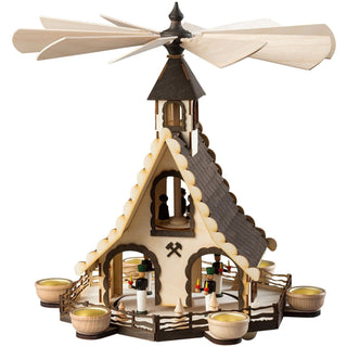 Weihnachtspyramide „Bergmänner“, 47 cm groß, aus naturbelassenem Holz mit dunklen Akzenten, in Form eines Hauses mit filigranen Bergmann‑Figuren im Inneren, umlaufenden Haltern für 6 Teelichte und großem Flügelrad, dekorativ und detailreich gestaltet.