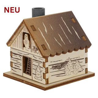 Räucherhaus „Drei Haselnüsse für Aschenbrödel®“ aus hellem Holz in rustikaler Hüttenoptik. Das detailreich gestaltete Häuschen zeigt winterliche Motive aus dem Märchenfilm, darunter die Eule Rosalie, verschneite Tannen und Haselnüsse. Der Schornstein dient als Rauchabzug und sorgt beim Räuchern für eine stimmungsvolle Winteratmosphäre.