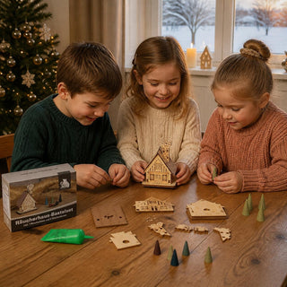 Drei Kinder bauen gemeinsam das Bastelset „Räucherhaus“ aus naturbelassenem Holz auf einem Tisch zusammen. Zu sehen sind die einzelnen Holzteile, eine Tube Leim, farbige Räucherkerzen sowie das teilweise montierte Räucherhaus. Im Hintergrund sorgen ein geschmückter Weihnachtsbaum und winterliche Dekoration für eine festliche Atmosphäre. Bastelset Räucherhaus inklusive Räucherkerzen und Leim, 8 cm.