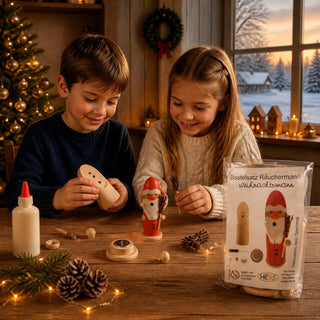 Bastelsatz Räuchermännchen „Weihnachtsmann“ aus naturbelassenem Holz, 12 cm. Auf einem Holztisch bauen zwei Kinder die Räucherfigur zusammen. Zu sehen sind einzelne Holzteile, Holzleim, ein bereits fertig gestaltetes Räuchermännchen im Weihnachtsmann-Design sowie die Produktverpackung des Bastelsatzes. Im Hintergrund schaffen ein geschmückter Weihnachtsbaum, Kerzenlicht und eine winterliche Fensterlandschaft eine stimmungsvolle Weihnachtsatmosphäre. Ideal für kreativen Bastelspaß in der Adventszeit.