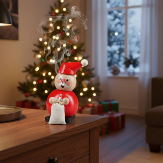 Räuchermännchen „Weihnachtsmann“ (12 cm), farbig gestaltet mit roter Mütze und Geschenksack, rauchend auf einem Tisch vor festlich geschmücktem Weihnachtsbaum und winterlicher Wohnkulisse dekoriert.