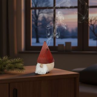 Räuchermännchen „Zwerg Roter Diddi“ (11 cm), farbig gestaltet mit roter spitzer Mütze und weißem Bart, rauchend auf einem Tisch vor gemütlicher Wohnkulisse mit winterlicher Fensteransicht dekoriert.