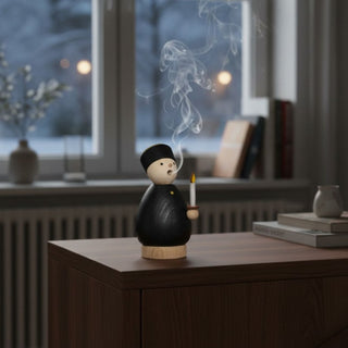 Räuchermännchen „Bergmann“ (9 cm), farbig gestaltet in traditioneller Bergmannskleidung mit schwarzer Tracht und Kerze, inkl. 5 Räucherkerzen, rauchend auf einem Tisch in ruhiger Wohnatmosphäre vor winterlicher Fensterkulisse dekoriert.