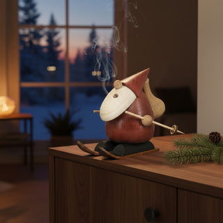 Räuchermännchen „Ski-Champion“ (10 cm), farbig gestaltet mit Skiern und Stöcken, rauchend auf einem Tisch vor winterlicher Wohnkulisse dekoriert.