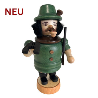 Farbig gestaltetes Räuchermännchen „Jäger“ aus Holz, etwa 20 cm hoch. Die Figur trägt grüne Jagdbekleidung mit Hut, Mantel und Knöpfen, sowie schwarze Schuhe. In einer Hand hält das Räuchermännchen ein kleines schwarzes Zubehörteil, in der anderen einen schmalen Stab.