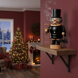Räuchermännchen „Schornsteinfeger“ (20 cm), farbig gestaltet mit schwarzer Uniform, Zylinder, Leiter und Besen, rauchend auf einem Wandregal in festlich dekorierter Wohnatmosphäre mit Weihnachtsbaum, Kamin und winterlicher Fensterkulisse im Hintergrund.