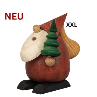 Farbiges Räuchermännchen „Weihnachtsmann Baumlieferservice“ aus Holz in modernem Design. Die Figur trägt eine rote Zipfelmütze und transportiert einen grünen Weihnachtsbaum auf der Schulter. Dekorative Räucherfigur in Rot, Naturholz und Schwarz, Höhe 24 cm.