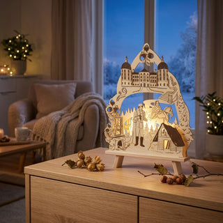 LED-Standleuchte „Drei Haselnüsse für Aschenbrödel®“ aus naturfarbenem Holz mit farbigen Akzenten (42 cm) und warmweißer LED-Beleuchtung. Das detailreich gestaltete Motiv zeigt zentrale Szenen und Elemente des Märchenklassikers, darunter Aschenbrödel auf einem Pferd, den Prinzen, ein Schloss, das Wohnhaus sowie mehrere Haselnüsse als dekorative Rahmenelemente. Filigrane Waldmotive, Bäume und weitere märchenhafte Details ergänzen die bogenförmige Gestaltung. Die Leuchte steht auf einer Holzkommode.