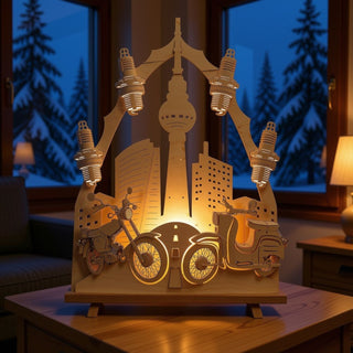 LED-Standleuchte „(N)Ostalgie Moped“ aus naturfarbenem Holz (44 cm) mit warmweißer LED-Beleuchtung. Das detailreich gestaltete Motiv zeigt zwei klassische Mopeds vor einer Stadtsilhouette mit Fernsehturm und modernen Gebäuden. Über der Szene sind vier stilisierte Zündkerzen angeordnet, während eine Straße in die beleuchtete Kulisse führt. Die dekorative Leuchte steht auf einem Holztisch in einem gemütlichen Wohnraum und setzt das nostalgische Zweiradmotiv stimmungsvoll in Szene.