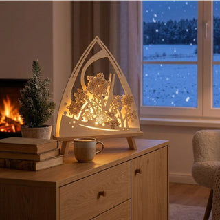 LED-Standleuchte „Eissterne“ aus naturfarbenem Holz (39 cm) mit warmweißer LED-Beleuchtung. Die dekorative Leuchte in spitz zulaufender Form zeigt filigran ausgeschnittene Schneeflocken und stilisierte Winterzweige, die vor einem sanft beleuchteten Hintergrund angeordnet sind. Die Leuchte steht auf einer Holzkommode in einem gemütlichen Wohnraum. Im Hintergrund sind ein Kaminfeuer sowie ein Fenster mit Blick auf eine verschneite Winterlandschaft und fallende Schneeflocken zu sehen.