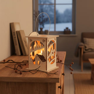 Laterne für 1 Teelicht oder mit LED‑Stripe „Drei Haselnüsse für Aschenbrödel®“, 16 cm, aus einfarbig abgesetztem Holz mit filigranen Märchenszenen inklusive Haus, Winterlandschaft und Figuren, dekorativ auf einem Holzsideboard mit Zweigen arrangiert, im Hintergrund Bücher und ein Fenster mit verschneiter Winterlandschaft, stimmungsvoll beleuchtet durch warmes Licht im Inneren.