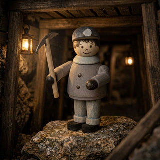 Miniatur „Bergmann mit Hacke“ (ca. 5 cm) aus naturbelassenem Holz, mit einer kleinen Figur in Bergmannskleidung und Grubenlampe, die eine Hacke in der Hand hält. Die Szene ist in einem detailreich gestalteten Bergwerksstollen mit Holzbalken, Gestein und warmer Beleuchtung inszeniert, wodurch eine authentische, rustikale Atmosphäre entsteht.