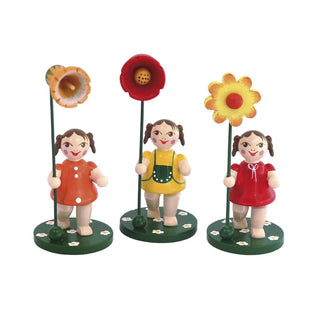 3 Blumenkinder Mädchen mit rot, gelb und organgenen Kleidern und jeweils einer Blume in der Hand 