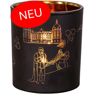 Aus der neuen Aschenbrödel-Kollektion. Ein Teelichtbehälter aus Glas mit mattschwarzer Außen- und goldener Innenseite. Als Motiv ist der Prinz mit dem gefundenen Schuh, das Aschenbrödel zu Pferd, einige Haselnüsse und das Schloss Moritzburg dargestellt. Bei schimmerndem Kerzenlicht leuchtet das Glas besonders hell schön. Bild 1.