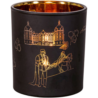 Der Teelichtbehälter aus Glas mit mattschwarzer Außen- und goldener Innenseite, passt perfekt zu Aschenbrödel-Fans. Als Motiv ist der Prinz mit dem gefundenen Schuh, das Aschenbrödel zu Pferd, einige Haselnüsse und das Schloss Moritzburg dargestellt. Bei schimmerndem Kerzenlicht leuchtet das Glas besonders hell schön. Bild 2.