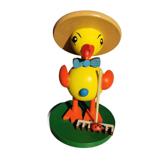 Gelbes Entenküken mit Hut und Rechen in der Hand.