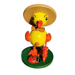 Gelbes Entenküken mit Hut und Schirm in der Hand.