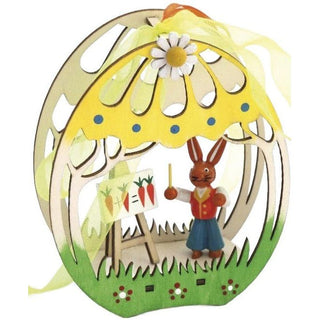 Farbiges Fensterbild aus Holz in 3D Optik. Das Festerbild ist grün und gelb bemalt. Im Bild befindet sich ein farbiger Osterhasenlehrer mit einer Schultafel.