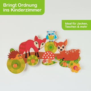 „Bunter Wandhaken für das Kinderzimmer mit Tiermotiven: Ein Igel, ein Fuchs, eine Eule und ein Rehkitz sind auf einer grünen Basis mit Pilzen dargestellt. Mehrere orangefarbene Knöpfe dienen als Haken zum Aufhängen. Oben links steht ‚Bringt Ordnung ins Kinderzimmer‘, oben rechts ‚Ideal für Jacken, Taschen & mehr‘.“