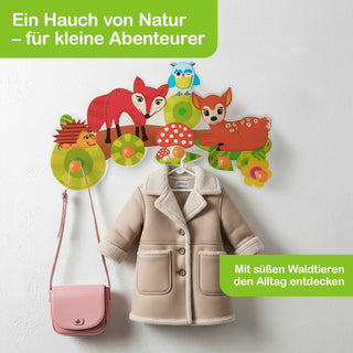 „Bunte Garderobe mit Waldtieren: Ein Fuchs, ein Reh, ein Igel und eine Eule sitzen auf einem Ast über Haken, an denen eine beige Kinderjacke mit Fellbesatz und eine rosa Umhängetasche hängen. Pilze und grüne Felder mit den Texten ‚Ein Hauch von Natur – für kleine Abenteurer‘ und ‚Mit süßen Waldtieren den Alltag entdecken‘ ergänzen das Design.“