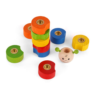 Ein Spielzeug-Set aus bunten Holzringen und einer kleinen Holzkugel mit aufgemaltem Gesicht. Die Ringe sind rot, grün, gelb, blau und orange, rund geformt und haben seitlich eine Aussparung sowie eine metallene Einlage in der Mitte. Die Holzkugel hat zwei grüne „Ohren“, geschlossene Augen und ein lächelndes Gesicht. Einige Ringe sind gestapelt, andere liegen locker um die Kugel verteilt.