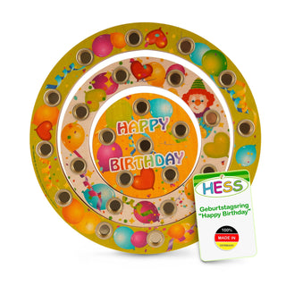 Geburtstagsring der Marke „Hess“ aus Holz mit drei konzentrischen, bunt dekorierten Kreisen. Jeder Kreis zeigt Ballons und Party-Motive. In der Mitte steht „HAPPY BIRTHDAY“ in bunten Buchstaben. Der Ring enthält mehrere Löcher für Kerzen oder Dekorationen. Ein Etikett unten rechts weist auf die Marke und die Herkunft „100% MADE IN GERMANY“ hin.
