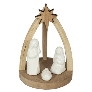 Krippenszene aus Holz mit den weißen Keramik-Figuren von Maria, Josef und dem Jesuskind. Die Figuren stehen auf einer runden Holzplattform und sind von einem hölzernen Bogen mit Stern überdacht.