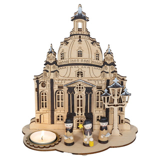 Kerzenhalter aus naturbelassenem Holz in Form der Dresdener Frauenkirche, 21 cm hoch, mit Platz für 1 Teelicht auf der linken Seite, drei kleinen Kurrende - Figuren im Vordergrund und einer Straßenlaterne auf der rechten Seite.
