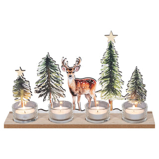 Dekorativer Kerzenhalter aus Holz mit vier Teelichthaltern aus Glas. In der Mitte steht ein Hirsch, umgeben von vier unterschiedlich großen Tannenbäumen mit teilweise goldenen Sternen an der Spitze. Alle vier Teelichter sind angezündet und erzeugen eine warme, gemütliche Atmosphäre.