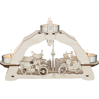 Dieser kleine hölzerne Lichterbogen in Natur kann mittels 3 Teelichter wunderbar Gemütlichkeit und Wärme vermitteln. Ideal für Motorrad-Freunde. Im Hintergrund ist der Berliner Fernsehturm dargestellt. Im Vordergrund sieht man ein nostalgisches Motorrad und ein in DDR-Zeiten erbautes Zweirad. Mittig im Bogen ist eine Zündkerze eingearbeitet.