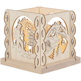 Holzteelichthalter zeigt auf 4 Seiten Berglandschaft, einen Wanderer mit Wegweisern und eine stilisierte Seilbahn. Beleuchtet von einem Teelicht.