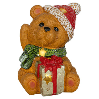 Weihnachtliche LED-Dekoration in Form eines Teddybären mit roter Mütze und grünem Schal. Der Bär hält ein Geschenk mit roter Schleife, das mit leuchtenden Sternen verziert ist. Die Figur ist 15,5 cm hoch, batteriebetrieben und mit Timerfunktion ausgestattet.