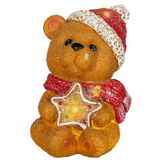 Weihnachtliche LED-Dekoration in Form eines Teddybären mit roter Mütze und Schal. Der Bär hält einen leuchtenden Stern mit bunten Punkten in den Pfoten. Die Figur ist 15,5 cm hoch, batteriebetrieben und mit Timerfunktion ausgestattet.