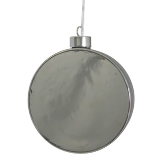 Runder, grauer LED-Glastaler mit feiner, warmweiß leuchtender Lichterkette im Inneren. Der Glastaler hängt an einem dünnen Faden und erzeugt durch das getönte Glas eine dezente Lichtstimmung. Unbeleuchtet