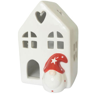 Kleines LED-Keramikhaus mit herz- und sternförmigen Ausschnitten, batteriebetrieben, 11 cm hoch, mit einem Wichtel in roter Mütze vor dem Haus. Die Fenster und Ausschnitte lassen warmes LED-Licht durchscheinen. Unbeleuchtet
