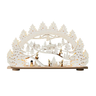 Schwibbogen aus Holz mit 4 Kindern und einem Schneemann bestückt. Mehrere Ringelbäumchen sind zu sehen. Der Schwibbogen zeigt eine Winterlandschaft.