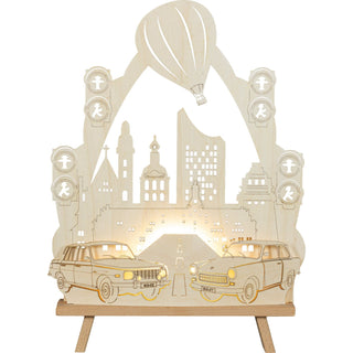 Die beleuchtete Deko-Spitze aus Holz in Natur ist ideal für Retro-Begeisterte.   Das Motiv zeigt den Weg nach Leipzig mit seinen schönsten Sehenswürdigkeiten. Die Spitze des Bogens ist ein aufsteigender Heißluftballon. Im Vordergrund sieht man einen Trabant und ein Wartburg. Seitlich sind Ampelanlagen mit Männchen eingearbeitet. Die Lichterspitze ist eine wunderbare Zusatzbeleuchtung für jeden Raum.