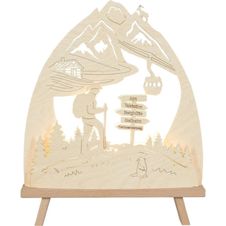 LED Standleuchte aus Holz zeigt Berglandschaft mit einem Wanderer auf einem Wanderweg, Wegweisern und einer stilisierten Seilbahn. Frontansicht, beleuchtet.