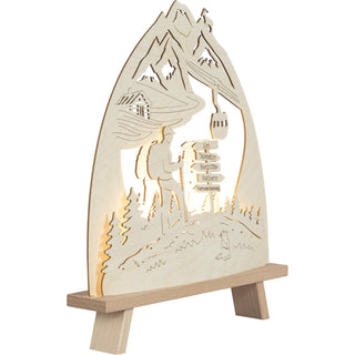 LED Standleuchte aus Holz zeigt Berglandschaft mit einem Wanderer auf einem Wanderweg, Wegweisern und einer stilisierten Seilbahn. Schrägansicht, linksseitig, beleuchtet.