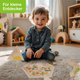 Ein kleines Kind sitzt auf einem Teppichboden in einem hellen Raum und spielt mit einem sechseckigen, bunten Puzzle. Im Hintergrund stehen Holzspielzeuge und Regale. Oben links im Bild steht „Für kleine Entdecker“ auf grünem Hintergrund.