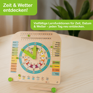 Holz-Lernuhr mit grünen Zeigern, umgeben von bunten Kreisen mit Zeitangaben. Links sind die Monate farbig aufgelistet, rechts die Wochentage. Unterhalb der Uhr befinden sich Symbole für Wetter und Jahreszeiten. Oben links steht „Zeit & Wetter entdecken!“, daneben „Vielfältige Lernfunktionen für Zeit, Datum & Wetter – jeden Tag neu entdecken.“ Die Uhr steht auf einem Tisch.