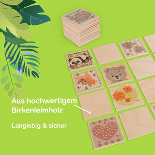 Holz-Memo-Spiel mit mehreren quadratischen Spielplättchen, die bunte Illustrationen wie Tiere und Blumen zeigen. Die Plättchen bestehen aus hochwertigem Birkenleimholz, wie durch einen Hinweis im Bild verdeutlicht wird. Zusätzlich steht im Bild „Langlebig & sicher“. In der oberen linken Ecke sind grüne Blätter zu sehen.